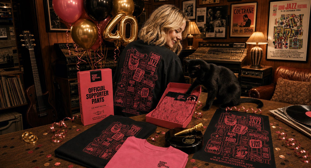 Soho Jazz Festival '26 collection, the tee, print, Official Supporter Pants and Top Brass on a Soho studio table with the cat